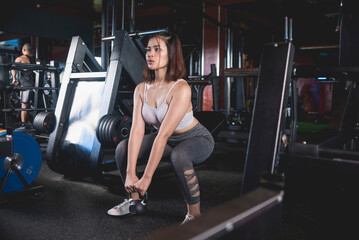Fototapeta na wymiar A young asian woman does a set of goblet squats with a kettlebell. Training at a modern gym.