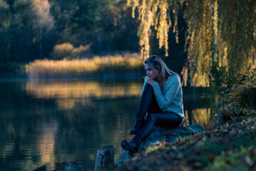 Fototapeta na wymiar Blonde Woman sitting on a lake with amazing reflection.