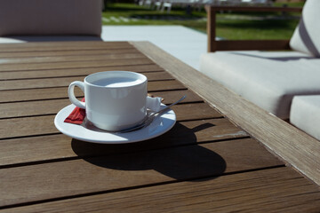 cup of sachet decaf milk and sugar on a wooden table in a summer setting