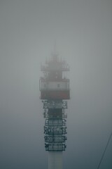 Vertical shot of a telecommunication tower covered in fog