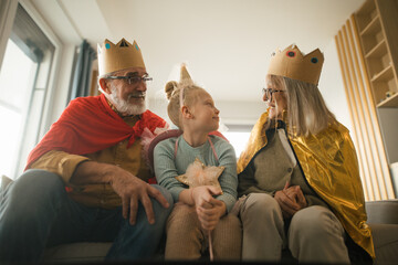 Grandparents playing with their little granddaughter, having costumes.
