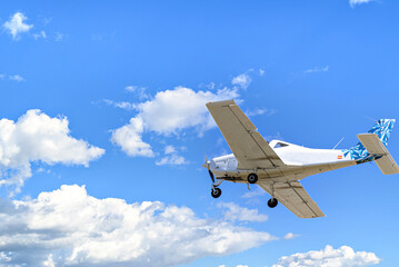 Single engine ultralight plane flying in the blue sky with white clouds	