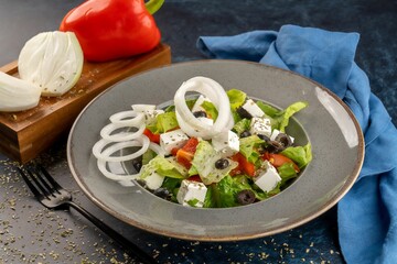 Closeup shot of a fresh Greek salad. Cheese with vegetables on a gray plate