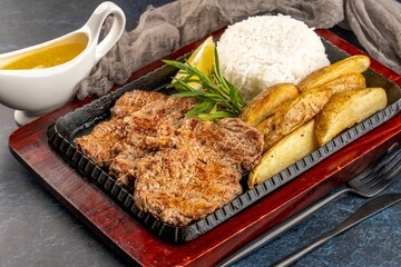 Closeup shot of grilled pork and potatoes with rice and yellow sauce