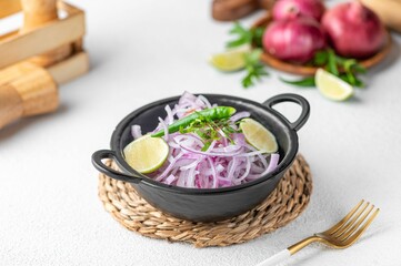 Gray bowl filled with freshly cut white onions, limes and parsley slices