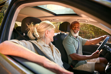 Senior Couple Enjoying Summer Day Trip Out Driving In Car Together