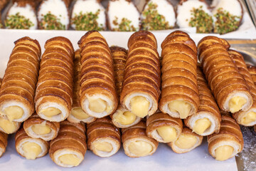 Obraz na płótnie Canvas Sweet tubes filled with cream close-up, sweet pastries, confectionery, flour products, street food. Organic food