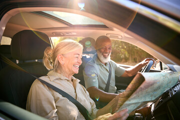 Senior Couple On Day Trip Out Driving In Car Reading Map