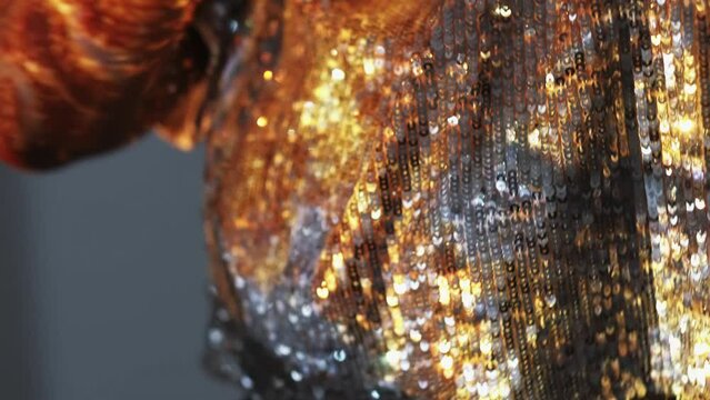 Magic lights. Festive look. Double exposure woman. Unrecognizable female in silver spangle crop top dancing on gray in golden shining sparkles overlay background lens flare.