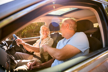 Senior Couple Enjoying Summer Day Trip Out Driving In Car Together
