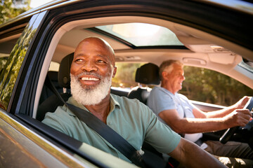 Two Senior Male Friends Enjoying Day Trip Out Driving In Car Together