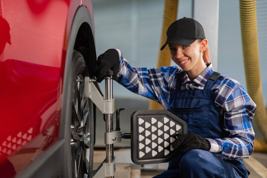 A female auto mechanic makes a camber. Woman working in a car service.