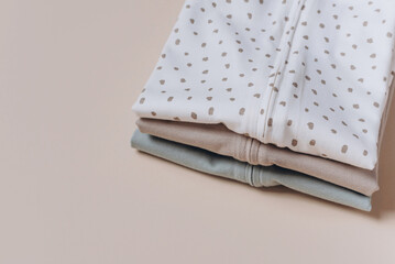 Set of organic cotton bodysuit, romper on beige background. Baby clothes. Fashion newborn clothes. Flat lay, top view. Copy space. Banner