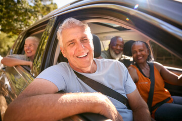 Portrait Of Group Of Senior Friends Enjoying Day Trip Out Driving In Car Together