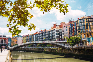 Bilbao downtown with the Nervion river, Ribera bridge and its colorful architecture on a sunny day. Enjoying a nice vacation in the Basque Country, Spain - obrazy, fototapety, plakaty