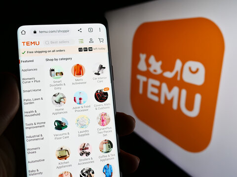 Stuttgart, Germany - 03-17-2023: Person holding cellphone with web page of American online shop company Temu on screen in front of logo. Focus on center of phone display.