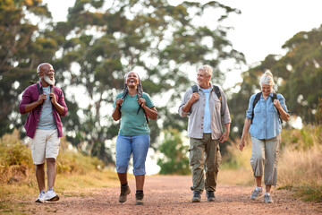 Group Of Active Senior Friends Enjoying Hiking Through Countryside Walking Along Track Together