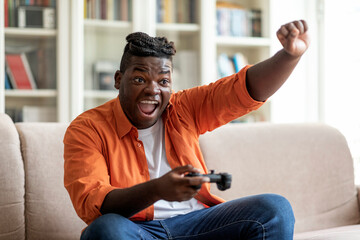 Emotional young black man playing video games at home © Prostock-studio