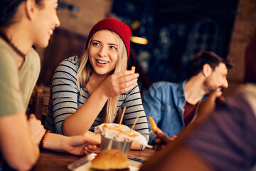 Young woman has fun while being with her friends in pub.
