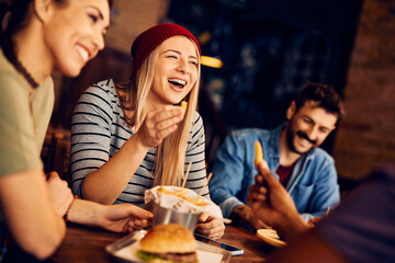 Carefree woman laughs while talking to her friends in pub.