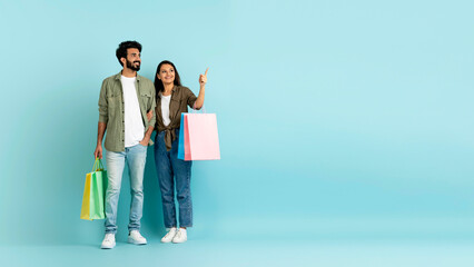 Loving multicultural couple go shopping together, copy space, carrying purchases