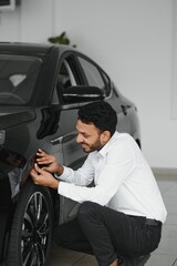 Fototapeta na wymiar A young Indian man chooses a new car at a car dealership