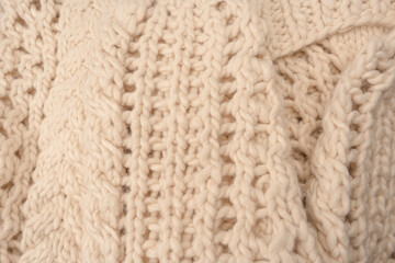 A fragment of beige knitted fabric, knitted from white sheep wool.