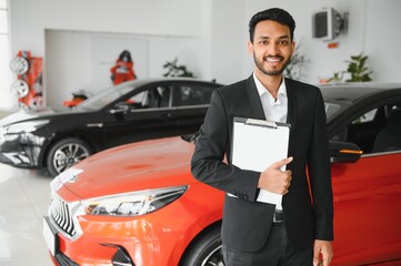 indian cheerful car salesman showing new car at showroom
