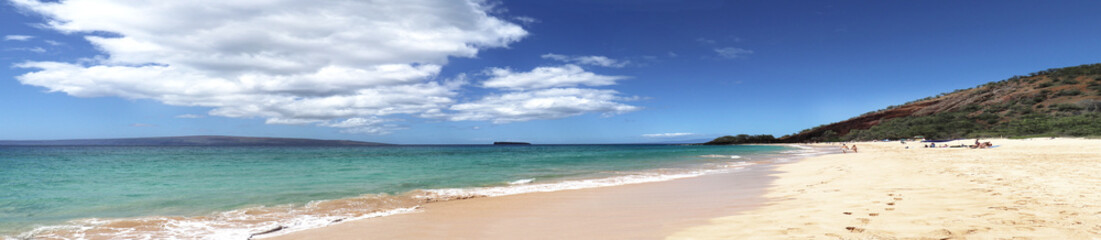 Panoramic sandy beach. Blue sea water and dramatic clouds. Maui, Hawaii, USA. 3 photo stitch. Unidentifiable sun bathers.  