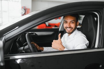 happy indian man checking car features at showroom