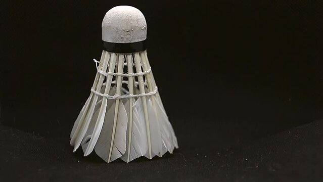 White badminton shuttlecock falls on a black background close-up