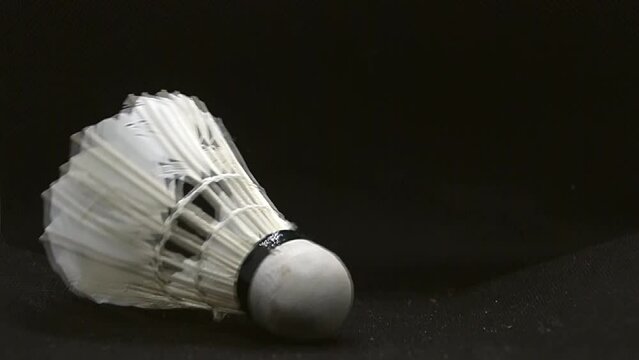 White badminton shuttlecock takes off on a black background close-up