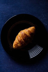 Top view of a croissant on a black plate