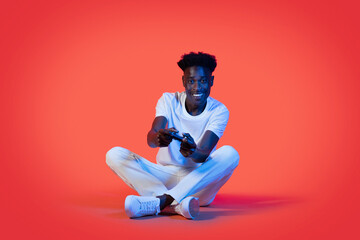 Joyful young black man playing video games, holding joystick