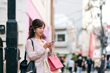Fototapeta premium ショッピングストリートでスマホを見る女性
