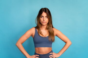 Smiling sportswoman with hands on waist in studio