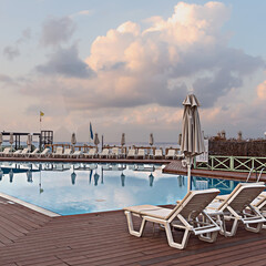 sun loungers and umbrellas on a wooden platform around the pool, located on the seashore. Hersonissos. Greece - 583982078