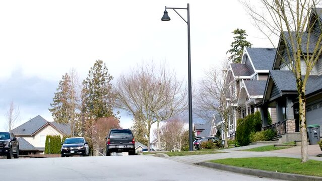 A row of a new houses in Surrey British Columbia, Canada. Front yards of the houses and street with trees and bushes. High quality photo