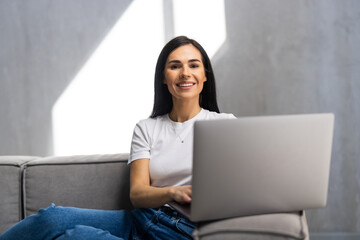 Young Woman using a laptop while relaxing on the couch