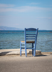 A wooden chair in front of seaside on the Aegina island in Greece.