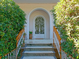 Corridor and stairs of an elegant house arched entrance and decorated white painted iron door. Travel to Athens, Greece.