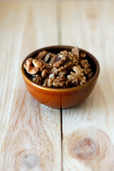 walnuts in a bowl on a wooden table, vertical use, space for text, walnuts as healthy food, isolated walnuts     