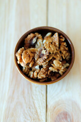 walnuts in a bowl on a wooden table, vertical use, space for text, walnuts as healthy food, isolated walnuts     