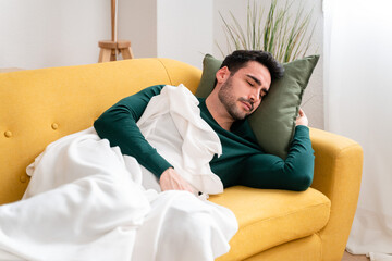 Young man lying on sofa and sleeping in cozy living room at home