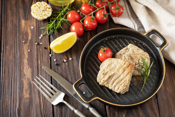 Cooked juicy tuna steak  with spices, tomatoes and rosemary on a stone plate. Restaurant food. Seafood. Rustic style. Copy space.