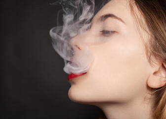 a woman with red lipstick on her lips lets out thick smoke