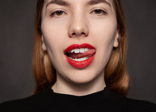 a woman with red lipstick shows her tongue