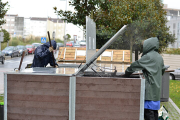 A worker is managing a community composter under the rain. Concept of recycling and sustainability