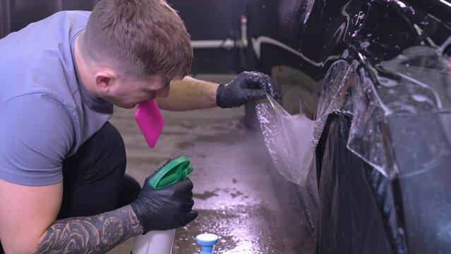 Man covering car with vinyl polyurethane tape. Films for the car. Sticker protective film on the car