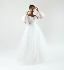 Model with dark skin in a white dress. Wedding make-up, wedding hairstyle. African American model posing in a white wedding dress.